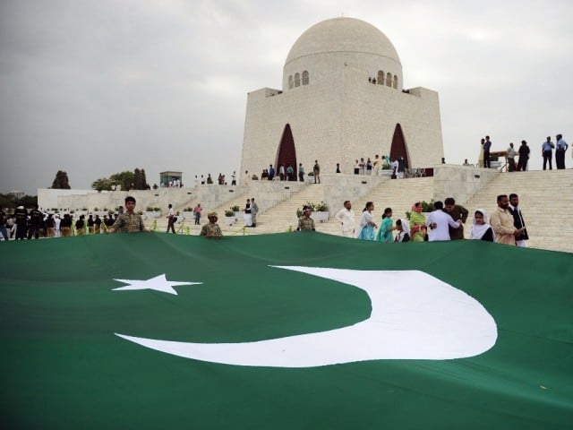 Pakistani students carry a giant national flag at the mausoleum of the founder of Pakistan Muhammad Ali Jinnah. PHOTO: AFP