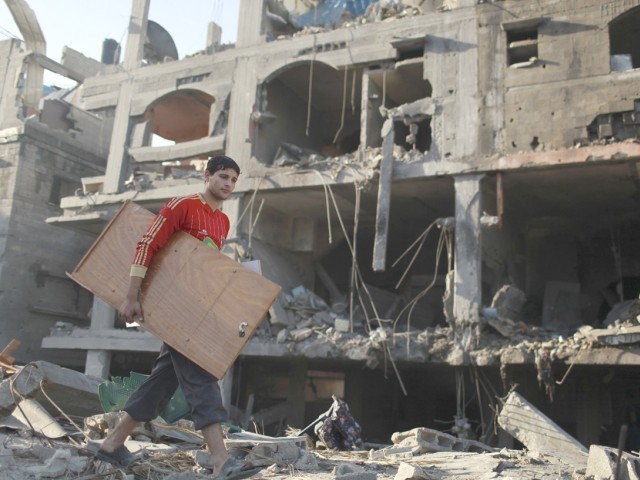 A Palestinian carries his belongings from a destroyed house after an Israeli air strike in the northern Gaza Strip. PHOTO : REUTERS